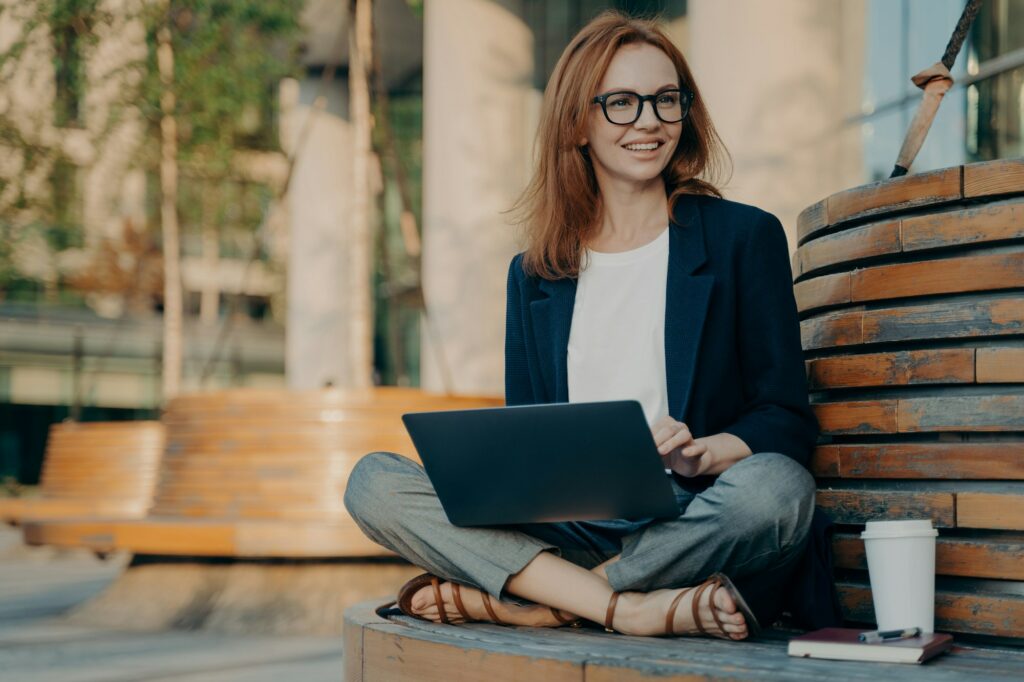 Pleased pretty redhead woman learns educational course on laptop computer