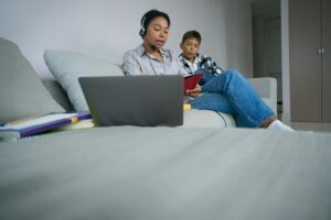 Boy watches his mother take online courses at home