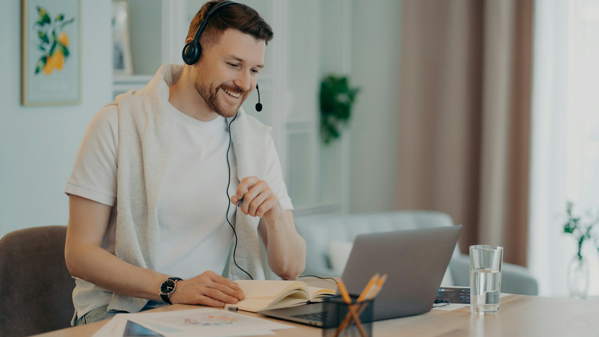 Happy man enjoying learning at home and using headset and laptop