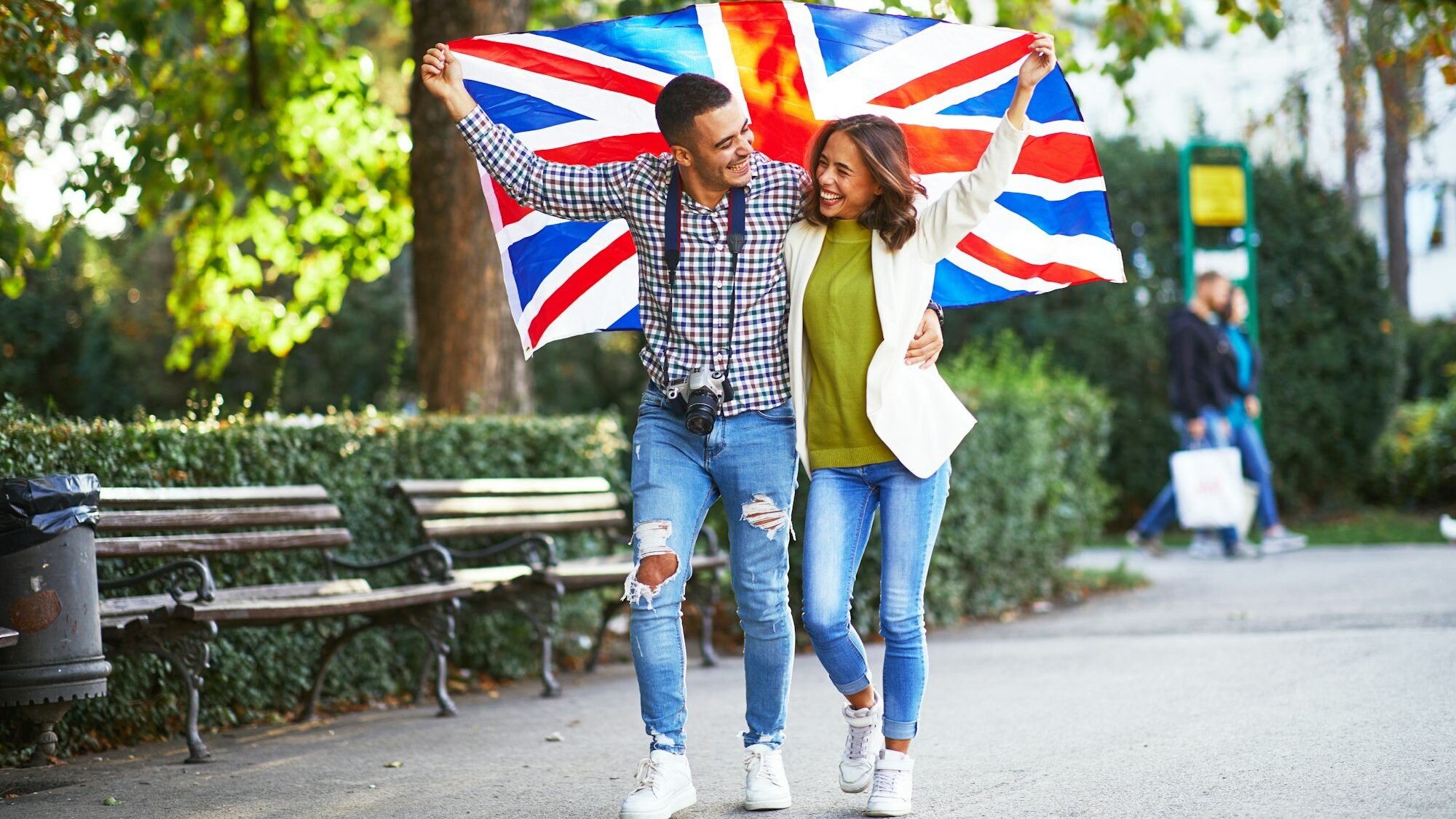 Happy young couple of tourists with a UK flag