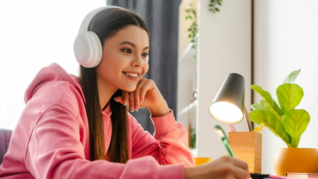 Young girl, teenager wearing headphones taking online course from home